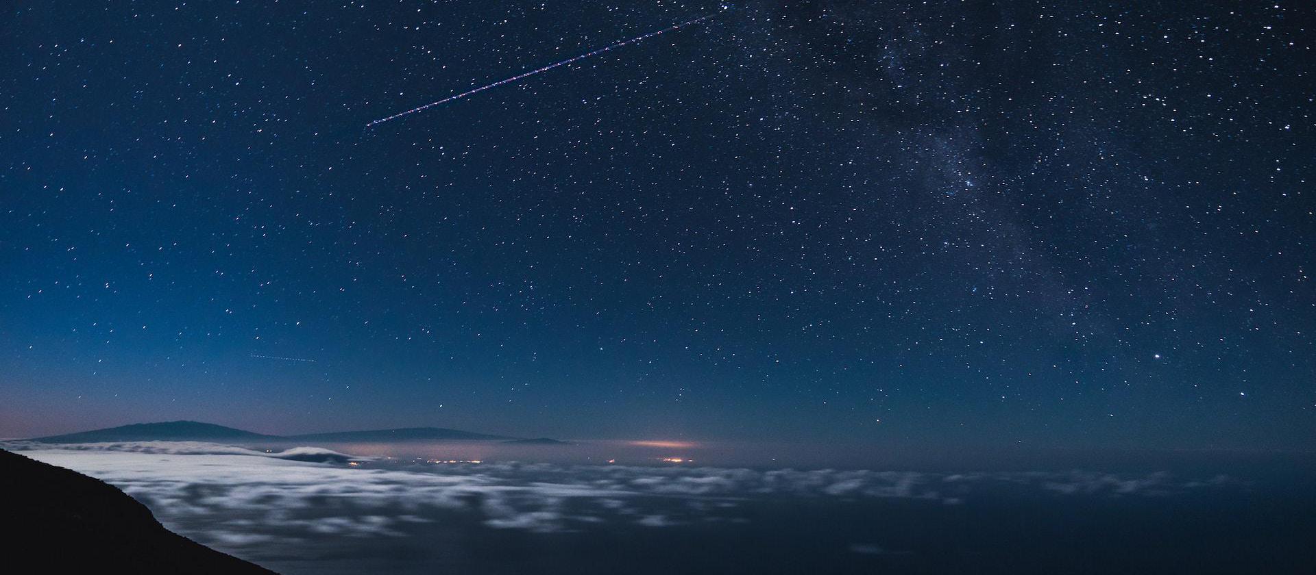 blue and black sky with stars and falling star at nighttime