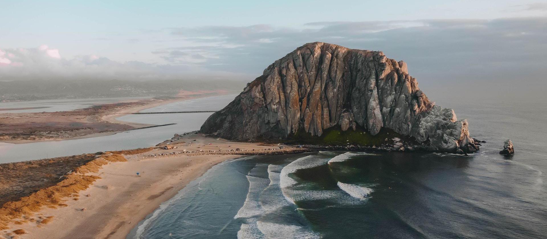 an aerial view of a beach with a large rock