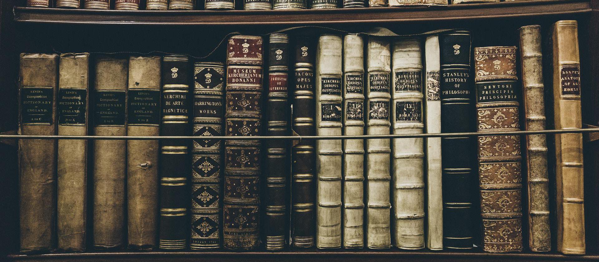 Image of old books on a bookcase shelf.