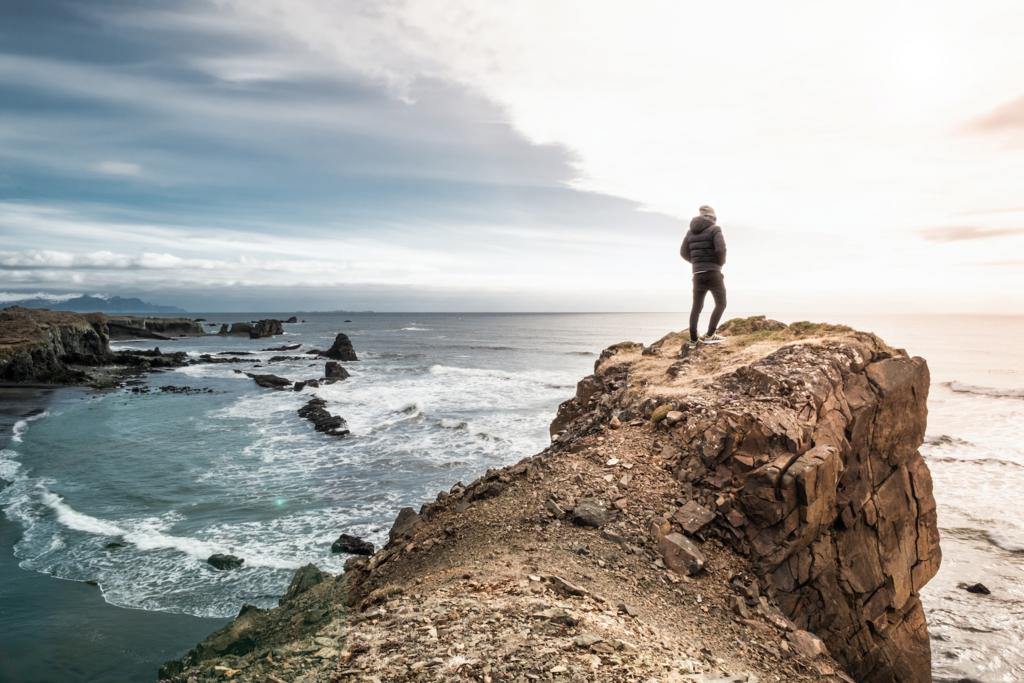 man on edge of cliff above the sea