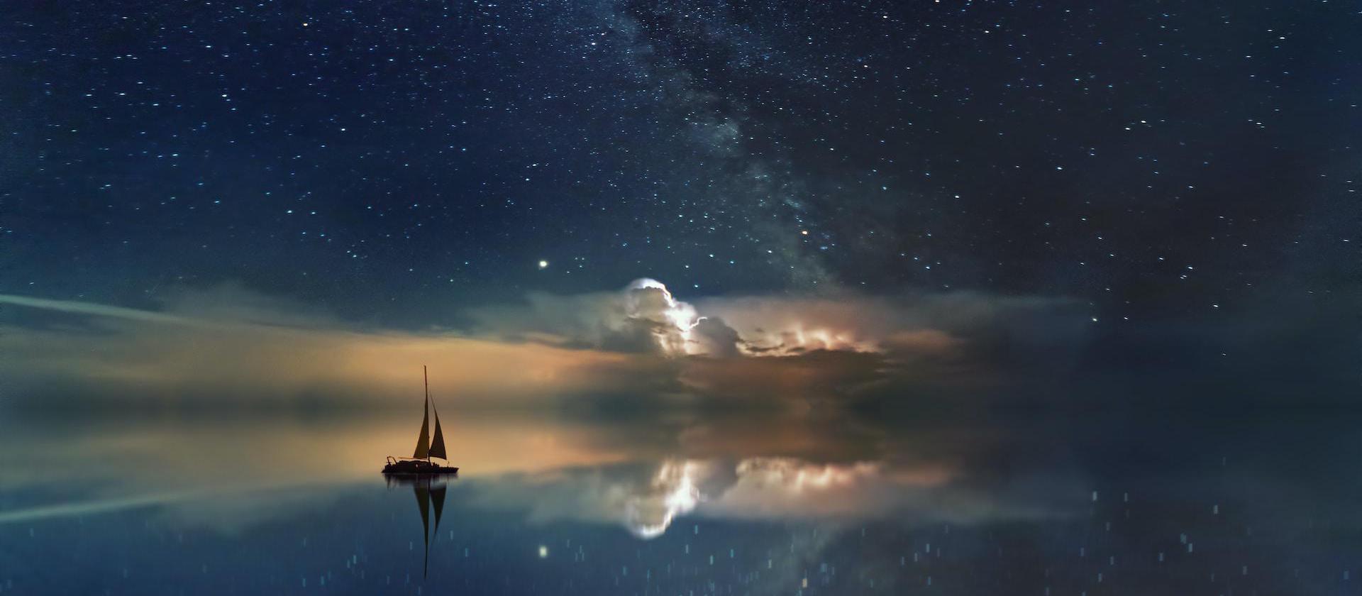 Image of a sailing ship on a sea of stars with a galaxy above.