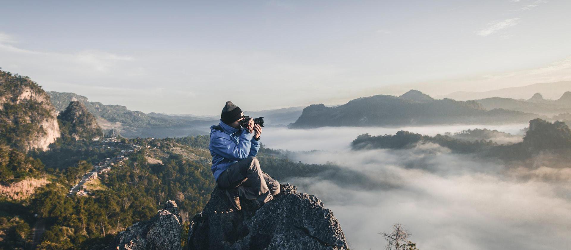 man on top of mountain taking pictures